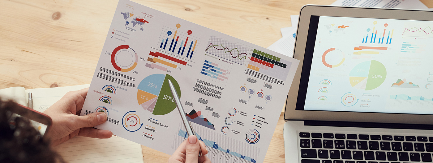 Osoba trzymająca kartkę z grafikami wykresów